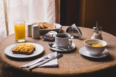 a table with breakfast foods and a glass of orange juice at El Patio Miraflores in Lima
