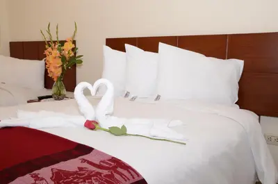 a bed with two swans towels and flowers on it at Aqua Hotel Cusco in Cusco