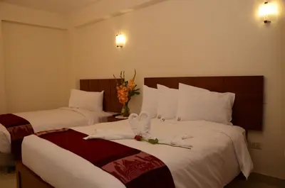 two beds in a hotel room with towels on them at Aqua Hotel Cusco in Cusco