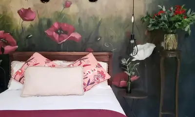 a bed with pink pillows and a vase of flowers at Niños Hotel Fierro in Cusco