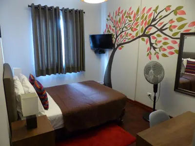 a bedroom with a bed with a tree painted on the wall at The Lighthouse Bed and Breakfast in Lima