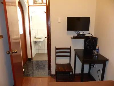 a room with a desk with a television and a chair at The Lighthouse Bed and Breakfast in Lima
