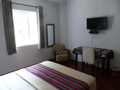 a room with a bed and a tv and a chair at The Lighthouse Bed and Breakfast in Lima