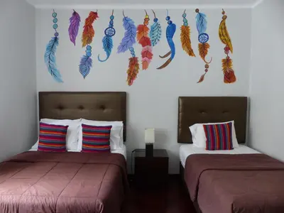 a bedroom with two beds with feathers on the wall at The Lighthouse Bed and Breakfast in Lima