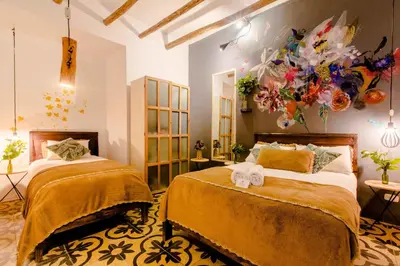 a bedroom with two beds and a painting on the wall at Niños Hotel Meloc in Cusco