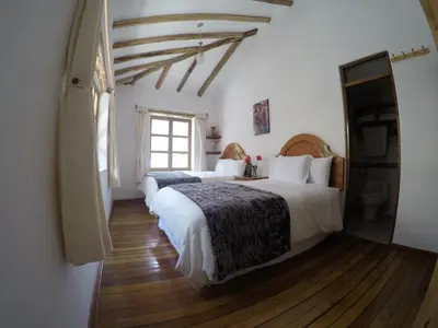 a bedroom with two beds and a window at Parwa Guest House in Ollantaytambo