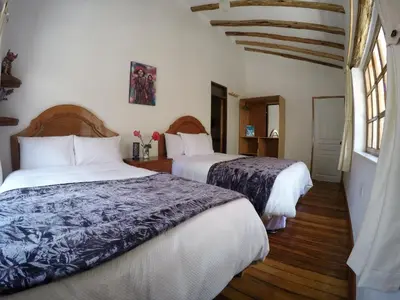 a bedroom with two beds and a window at Parwa Guest House in Ollantaytambo