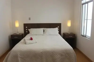 a bedroom with a large bed with two night stands at Caihuayna Apart Hotel in Paracas