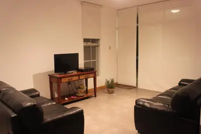 a living room with two leather couches and a television at Caihuayna Apart Hotel in Paracas