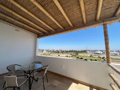 a dining room with a table and chairs and a large window at Caihuayna Apart Hotel in Paracas