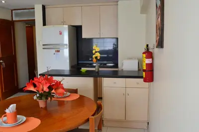 a kitchen with a table and a white refrigerator at Suite Service Apart Hotel in Lima