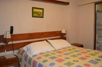 a bedroom with a bed with a colorful comforter at Suite Service Apart Hotel in Lima