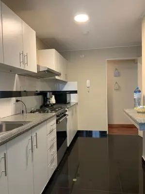 a kitchen with white cabinets and a stove top oven at MLA apartments - Kennedy in Lima