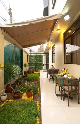 a patio with tables and chairs and a garden at Hotel Manhattan Inn Airport in Lima
