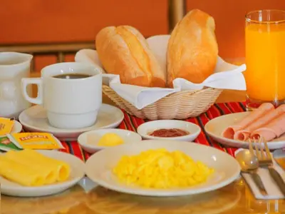 a table topped with plates of breakfast foods and drinks at Hotel Manhattan Inn Airport in Lima