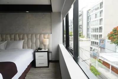 a bedroom with a bed and a large window at Hotel Ferré Miraflores in Lima