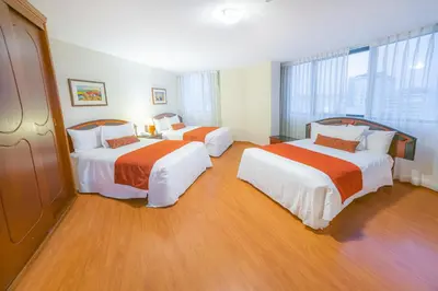 a hotel room with two beds with orange and white sheets at Miraflores Colon Hotel in Lima