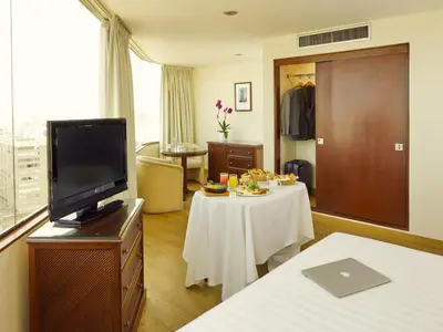 a hotel room with a bed and a tv and a table at Hotel Estelar Miraflores in Lima