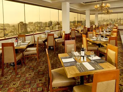 a restaurant with tables and chairs and a view of the city at Hotel Estelar Miraflores in Lima
