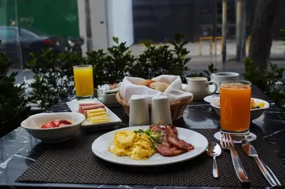 a breakfast table with breakfast foods and orange juice at Estelar Apartamentos Bellavista in Lima