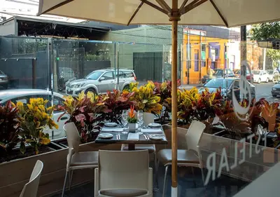 a table with chairs and an umbrella on a street at Estelar Apartamentos Bellavista in Lima
