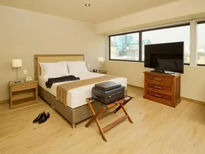 a bedroom with a bed and a flat screen tv at Estelar Apartamentos Bellavista in Lima