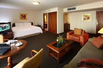 a hotel room with a bed and a living room at LUOXO Hotel in Lima