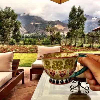 a person holding a bowl on a table with a view at Luxury House & Unique Experience at Sacred Valley, Urubamba, Cusco in Urubamba