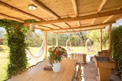 a wooden pergola with a wooden table with flowers on it at Luxury House & Unique Experience at Sacred Valley, Urubamba, Cusco in Urubamba