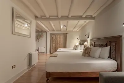 a bedroom with two beds with white walls and wooden floors at Antigua Casona San Blas in Cusco