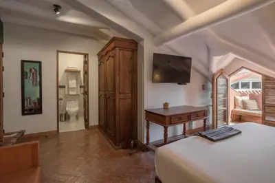 a bedroom with a bed and a desk and a television at Antigua Casona San Blas in Cusco
