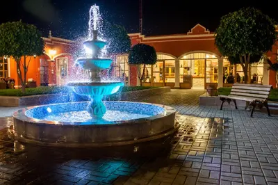 a fountain in the middle of a courtyard at night at Hacienda San Juan Resort in Ica