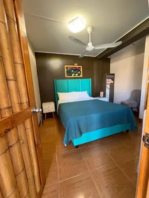 a bedroom with a bed with a blue bedspread at La Casa de Bamboo in Ica