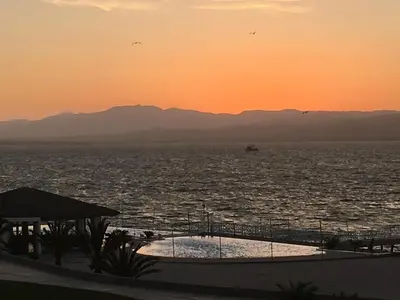 a view of the ocean at sunset with a boat in the water at Paracas vista al mar in Paracas