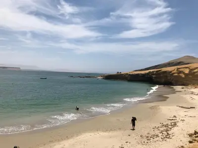 two people walking on a beach near the ocean at Paracas vista al mar in Paracas