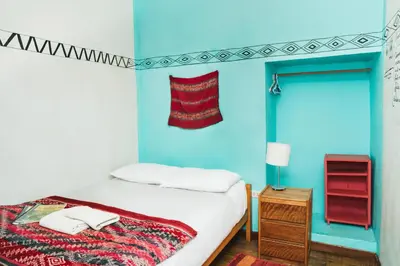 a bedroom with blue walls and a bed with white sheets at Backpacker La Bo'M in Cusco