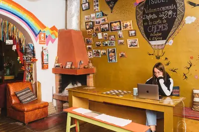 a woman sitting at a table with a laptop at Backpacker La Bo'M in Cusco