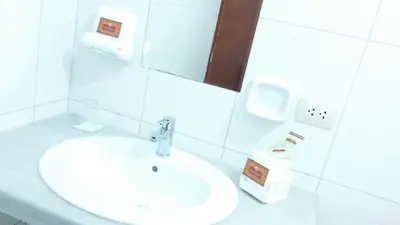 a white bathroom with a sink and a mirror at Amazonia Siu Hostal in La Merced