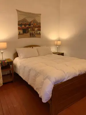 a large bed in a bedroom with two lamps at Hospedaje Killipata in Cusco