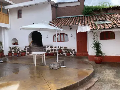 a white house with a table and an umbrella at Hospedaje Killipata in Cusco