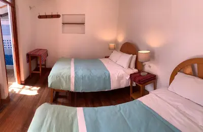 a bedroom with two beds and two tables with lamps at Hospedaje Killipata in Cusco
