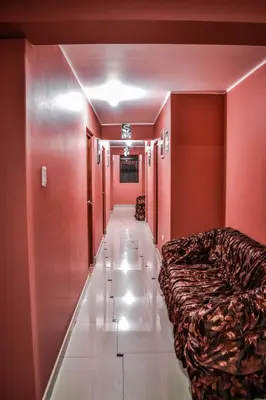 a hallway with a bed in a room with red walls at Hostal Berlin in Jauja