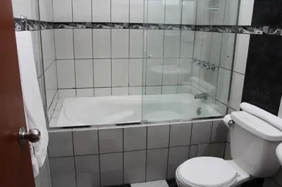 a bathroom with a tub and a toilet and a sink at Hotel El Farolito in Lima
