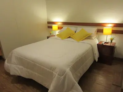 a bedroom with a large white bed with yellow pillows at Cusco House in Cusco