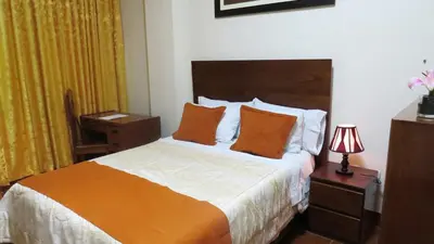 a hotel room with a bed with orange and white sheets at Victtorios Hotel in Satipo