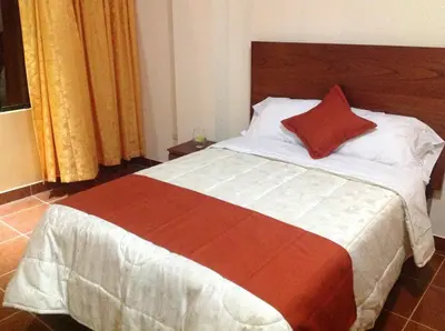 a bed with a red pillow on top of it at Victtorios Hotel in Satipo