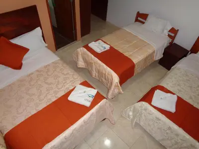 a room with three beds with towels on them at Victtorios Hotel in Satipo