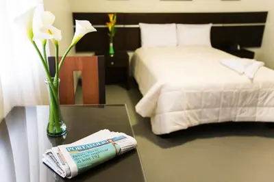 a hotel room with a bed and a table with a book at Mariategui Hotel & Suites in Lima