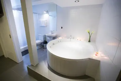 a white bathroom with a large tub and a toilet at Mariategui Hotel & Suites in Lima