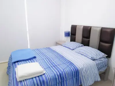 a bedroom with a bed with blue and white sheets and pillows at Departamento Monterrico in Lima